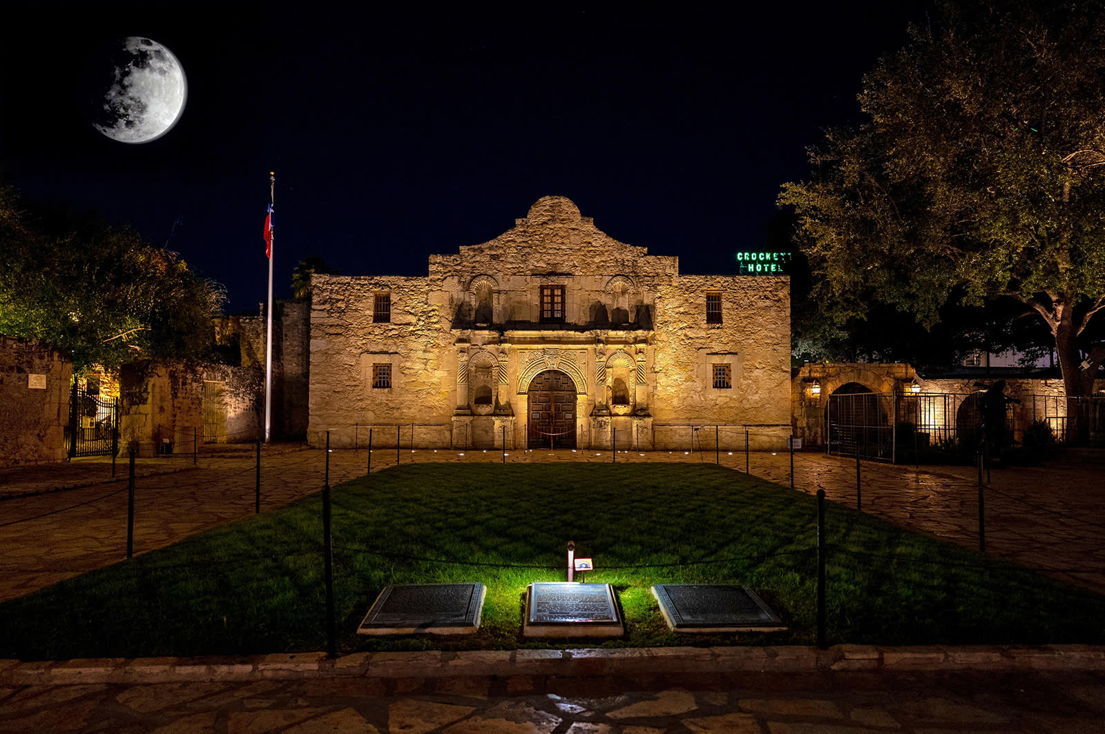 The Alamo lit at night under a full moon